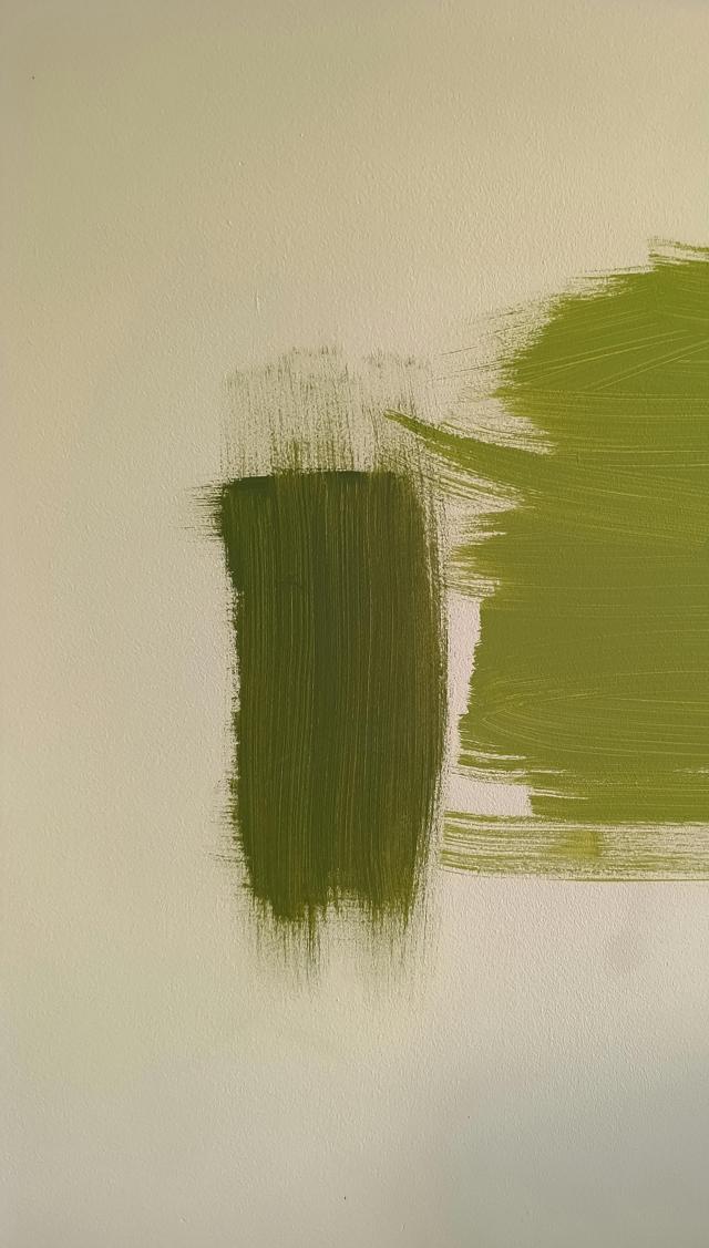 Close-up of green paint swatches on a canvas with textured brush strokes.