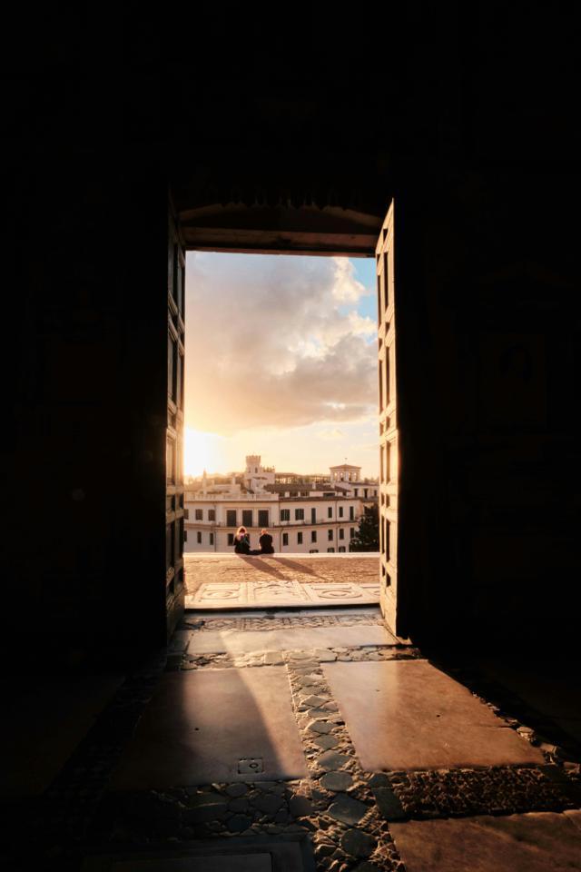 Captivating sunset framed by a Roman doorway, overlooking the cityscape of Rome, Italy.